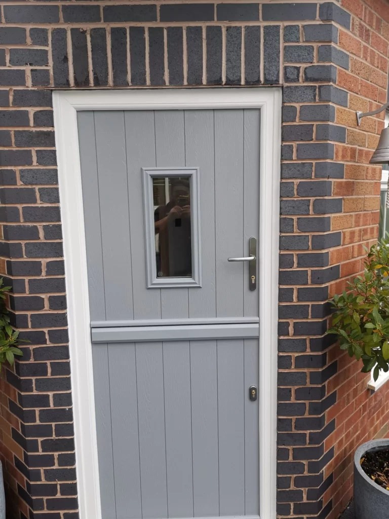 A grey composite stable door with a small glazed panel
